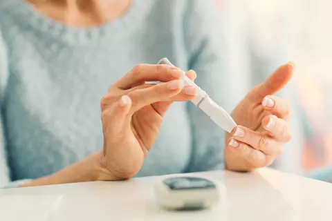 Dame misst ihren Blutzuckerspiegel mit dem Insulin-Pen