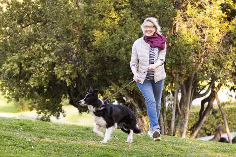 Flotte Dame geht mit Hund im Park spazieren