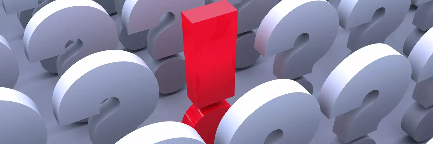 Rotes Ausrufezeichen zwischen weißen Fragezeichen