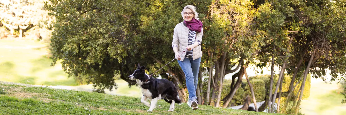 Flotte Dame geht mit Hund im Park spazieren