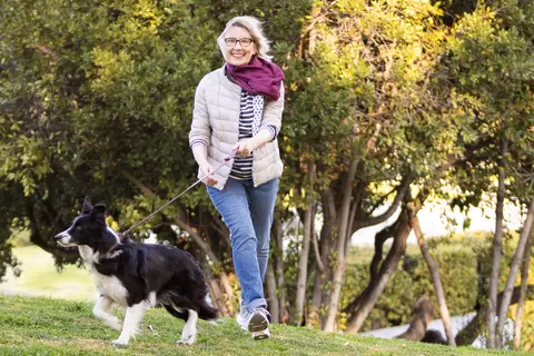Flotte Dame geht mit Hund im Park spazieren