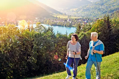 Paar wandert mit Nordic Walking Stöcken über Wiesen