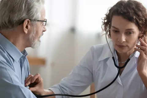 Ärztin verwendet ein Stethoskop, um einen Patienten während einer medizinischen Untersuchung abzuhören.