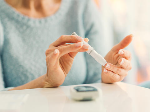 Dame misst ihren Blutzuckerspiegel mit dem Insulin-Pen