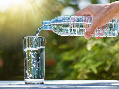 Ein Glas wird mit Wasser befüllt, um ausreichend Flüssigkeit auch an heißen Tagen zu sich zu nehmen